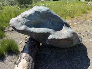A naturally weathered boulder with an unusual hollowed form, resting at the site.