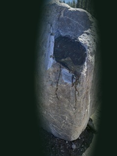 A rough boulder with a polished window cut into its surface, revealing deep green nephrite beneath the weathered exterior, shown at full scale.